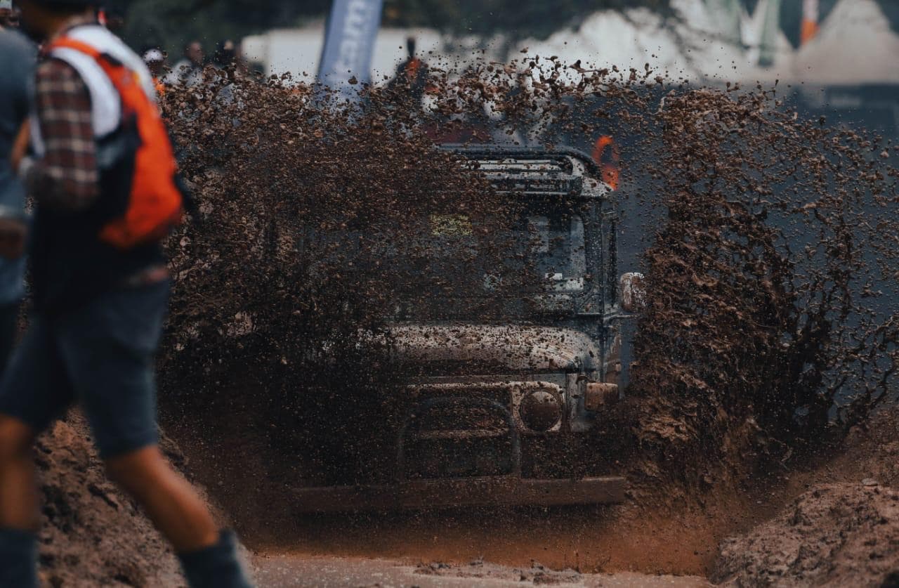 A truck sends a wall of mud into the air as it powers through the pit