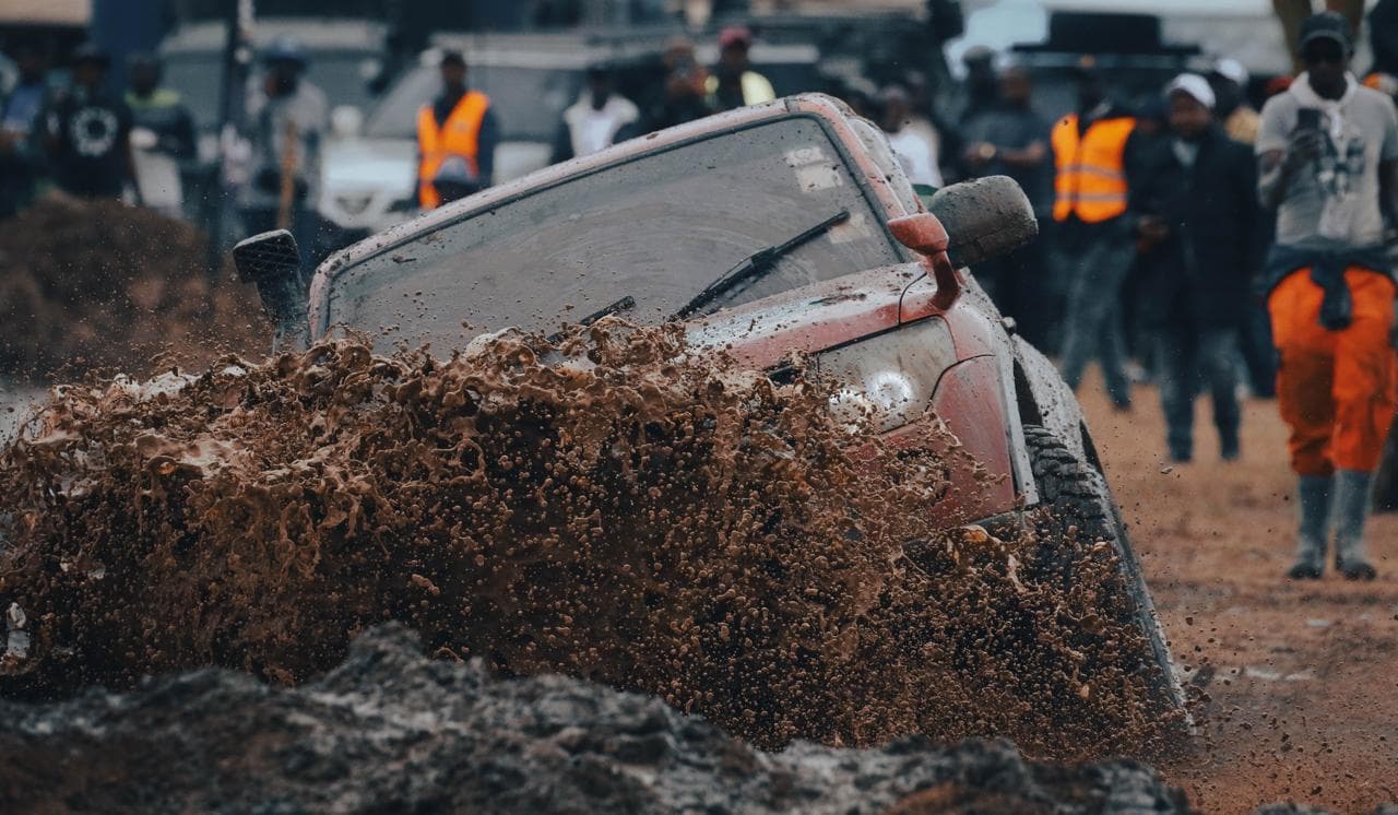Marshals in high-visibility vests holding the line as a 4x4 tears through the mud pit