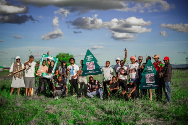 A group of Mud4Green volunteers celebrating a tree-planting drive, holding sustainability signage
